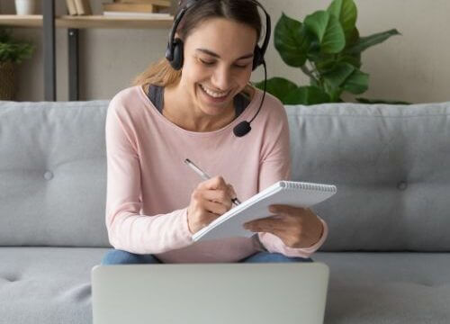 a woman taking notes while listeting and watching